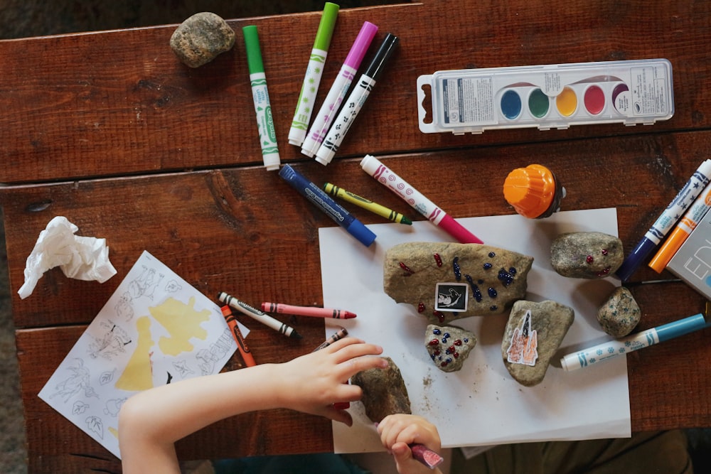 A child's hands painting and making at a craft table.