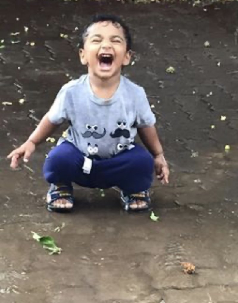 A child crouching in a puddle, laughing, during a playtime learning-style evaluation.